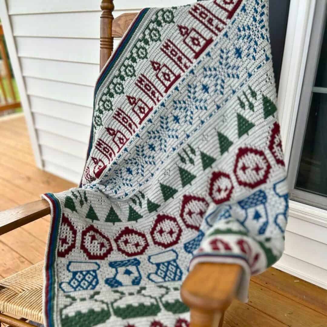 Decorative crochet blanket with holiday-themed mosaic pattern in red, green, and blue. Perfect for J.